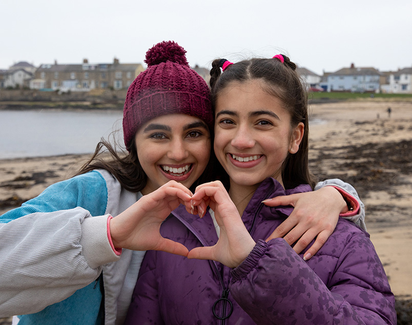 Photograph of 2 young girls holding their hands together to form a heart shape